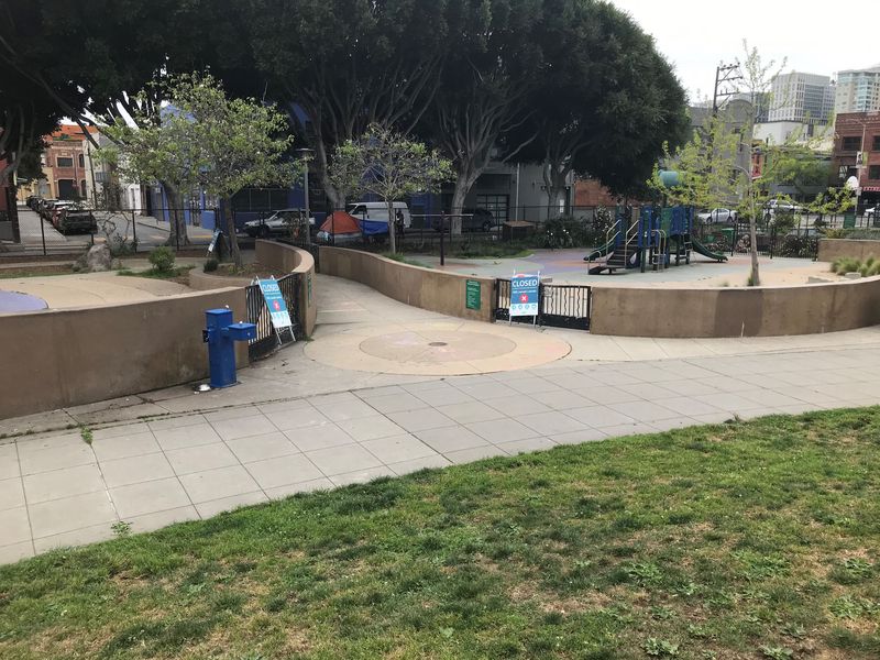 游乐区之间的步道,四周有水泥矮墙和新冠防疫安全标识