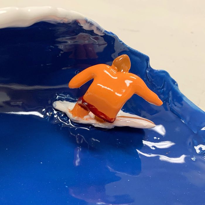glazed ceramic piece of a surfer and an ocean wave