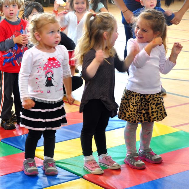 Niños pequeños sobre un tapete colorido en un gimnasio