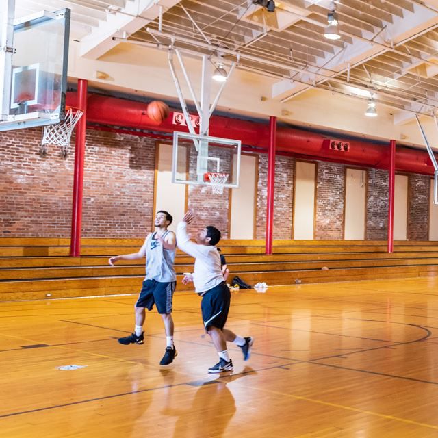 Young men playing basketball in indoor gym