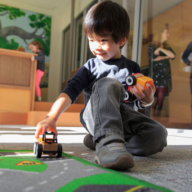 Little boy playing with toy cars on the floor