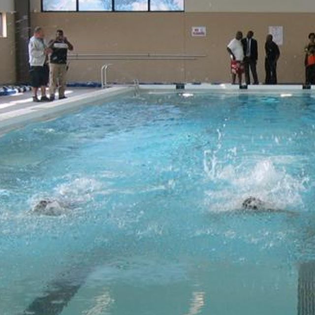 Personas nadando en la piscina y de pie a su alrededor