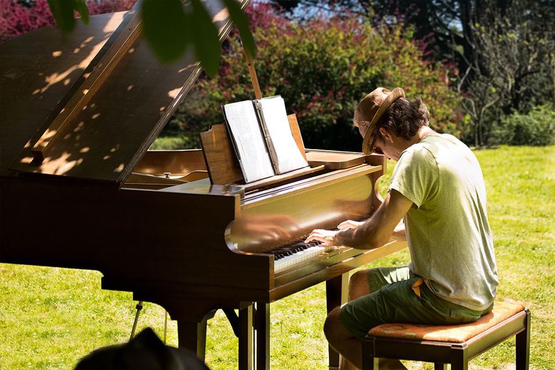 A person playing a piano tucked among flowers in the Botanical Garden